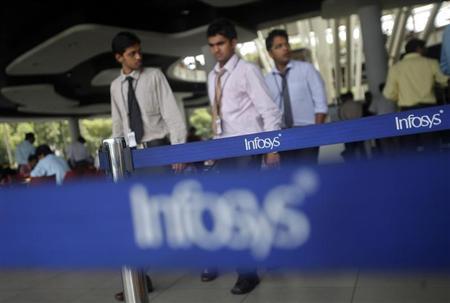 Employees of Indian software company Infosys walk past Infosys logos at their campus in the Electronic City area in Bangalore